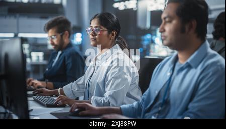 Young Team of Female and Male South Asian Specialists Working on Computers and Having a Conversation at a Workplace. Two Programmers Discussing a Solution for Their New Software Upgrades Stock Photo