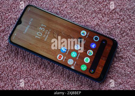 Terengganu, Malaysia - 2 August 2024 : Closeup of realme phone with apple iphone wallpaper on display on red background Stock Photo