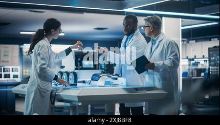 Diverse Team of Industrial Robotics Specialists Gathered Around Table With a Mobile Robot. Engineers In Lab Coats Discussing an Automated Robotic Delivery Machine with Artificial Intelligence Stock Photo