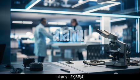 Workplace with a Modern Digital Microscope in a Research and Development Facility. Two Engineers or Scientists Working in High Tech Laboratory with Modern Equipment in the Background Stock Photo