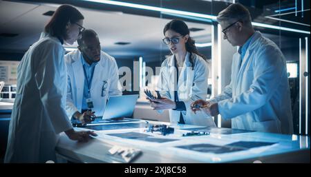Team of Tech Scientists Having a Group Meeting in a Research and Development Facility at a Robot Manufacturing Factory. Engineers Examining an Innovative Robotic Bionic Hand Concept Stock Photo