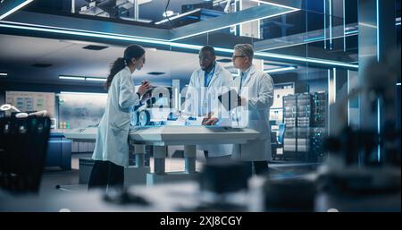 Diverse Team of Industrial Specialists Working on Remotely Controlled Mobility Robot in a Research Facility. Young Male and Female Engineers Discussing an Autonomous AI Delivery Assistant Stock Photo