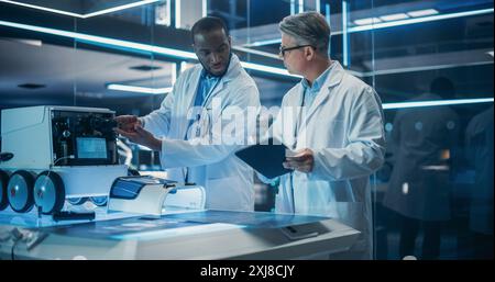 Portrait of Two Diverse Male Industrial Robotics Specialists Working on a Mobile Robot. Caucasian And Black Engineers In Lab Coats Discussing an Automated Robotic Delivery Assistant with AI. Stock Photo
