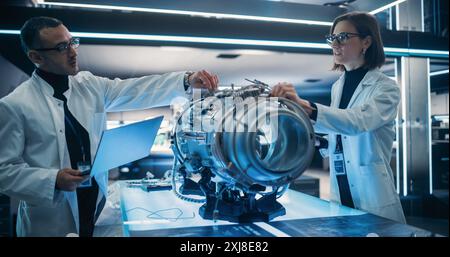 Professional Multicultural Team of Female and Male Engineers Working On Industrial Jet Turbine in Factory Development Workshop. Tech Facility with Machines, Computers and Research Equipment Stock Photo