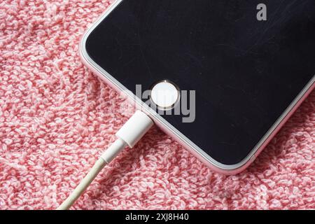 Closeup of black apple iphone is charging on red background Stock Photo