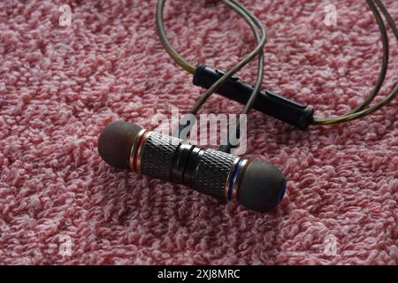 Closeup of brown stainless steel wired earphone on red fabric. High quality magnet earphone. Stock Photo