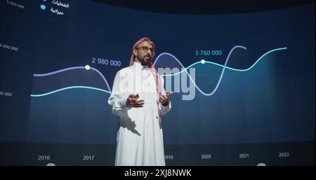 Successful Middle Eastern Speaker Presenting a New Product, Showing Infographics, Statistics Animation on Big Screen. Talking About Business Performance at a Press Conference Stock Photo