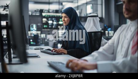 Beautiful Middle Eastern Computer Scientist Wearing a Hijab, Working on PC in a Technological Corporate Office. Young Muslim Woman Writing Software Code for an Innovative Online Service Project Stock Photo