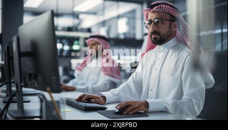 Portrait of a Thoughtful Middle Eastern Engineer Working on Computer in a Technological Corporate Office. Manager Working with Colleagues on Innovative Internet and Software as a Service Project Stock Photo
