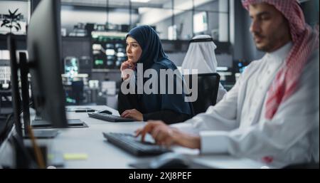 Portrait of a Thoughtful Middle Eastern Female Working on Computer in a Technological Corporate Office. Young Woman Writing Software Code for an Innovative Internet and Software as a Service Project Stock Photo