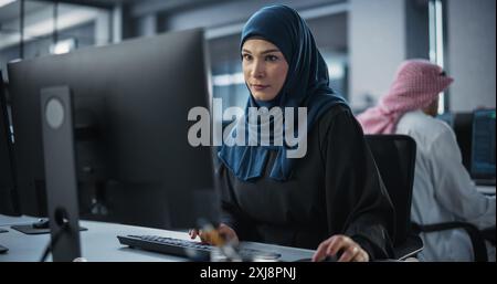 Young Arab Female Artificial Intelligence Engineer Working on Computer in a Technological Office. Young Middle Eastern Specialist Writing Software Code for an Innovative Big Data Blockchain Project Stock Photo