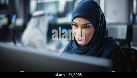 Portrait of a Thoughtful Middle Eastern Engineer Working on Computer in a Technological Corporate Office. Young Woman Writing Software Code for an Innovative Internet and Software as a Service Project Stock Photo