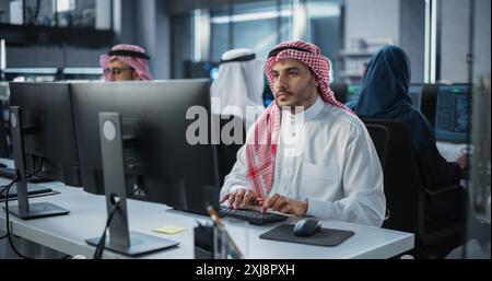 Team of Talented Young Middle Eastern Professionals Working in a Technological Research and Development Agency. Computer Screens with Software Code and Technical Neural Network Diagrams Stock Photo