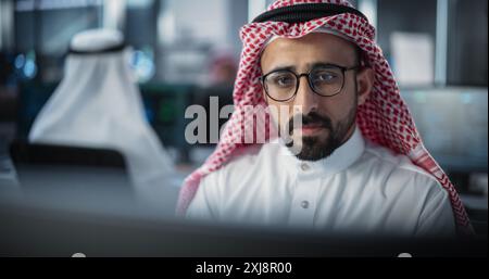 Portrait of a Thoughtful Middle Eastern Engineer Working on Computer in a Technological Corporate Office. Manager Working with Colleagues on Innovative Internet and Software as a Service Project Stock Photo