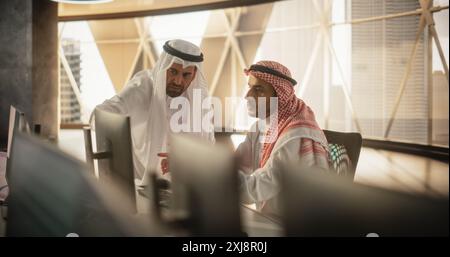 Two Young Middle Eastern Colleagues Working in a Business Software Development Company. Muslim Team Leader Updating Economic Strategist on a Financial Market News and Trends Stock Photo
