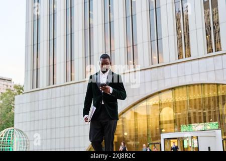 black businessman leaving office walking with suit and laptop in hand Stock Photo