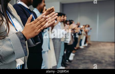 Colleagues clapping hands in celebration during a business conference presentation, highlighting a supportive workplace environment. Stock Photo