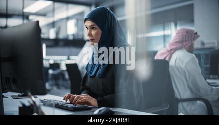 Portrait of a Smart Focused Middle Eastern Engineer Working on Computer in a Technological Corporate Office. Young Arab Woman in Hijab Developing Software for an Innovative Internet Service Provider Stock Photo