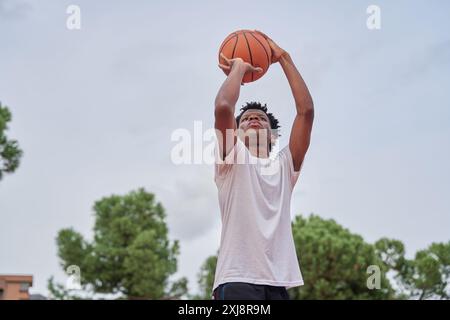 black man shooting basketball on a court in the city Stock Photo