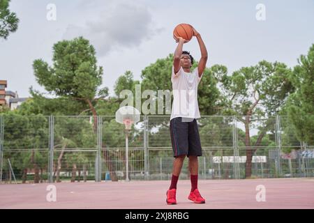 black man shooting basketball on a court in the city Stock Photo