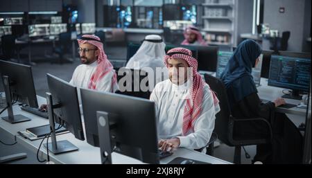 Team of Talented Young Middle Eastern Professionals Working in a Technological Research and Development Agency. Computer Screens with Software Code and Technical Neural Network Diagrams Stock Photo