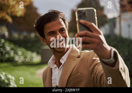 young indian man in suit and smiling taking a selfie with his smartphone Stock Photo