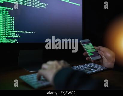 Code, hands and technology with hacker typing on keyboard to break cyber security firewall at night. Computer, data theft and phone with person in Stock Photo