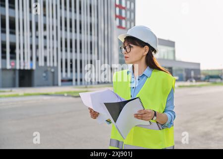 Industrial worker female builder with working documents, outdoor construction Stock Photo