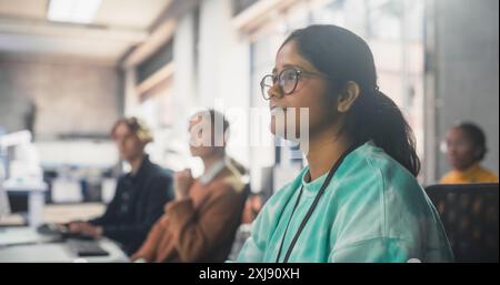 Portrait of a South Asian Female Student Studying in College with Diverse Classmates. Indian Girl Listening to Teacher, Using Computer to Apply Her Knowledge to Acquire New IT Skills in Class Stock Photo
