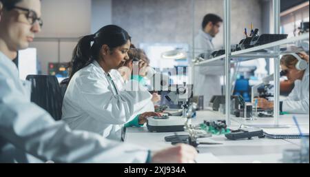 Diverse Team of Multiethnic Young Scientists Passing Internship in a Modern High Tech Laboratory. Students Working in Advanced Lab with Science Equipment. Microchip Design and Electronics Development Stock Photo