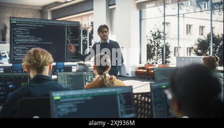 Teacher Giving Computer Science Lecture to Diverse Multiethnic Group of Female and Male Students in a College Room. Projecting Slideshow with Programming Code. Explaining Information Technology Stock Photo
