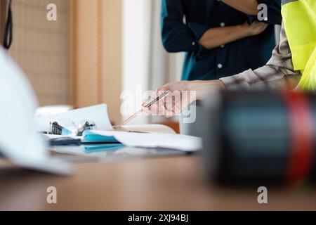 Engineer Discussing Project Plans with Colleague in Modern Office Setting, Reviewing Blueprint and Technical Drawings Stock Photo