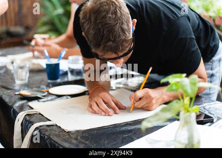 Man with sunglasses drawing standing upright leaning on table Stock Photo