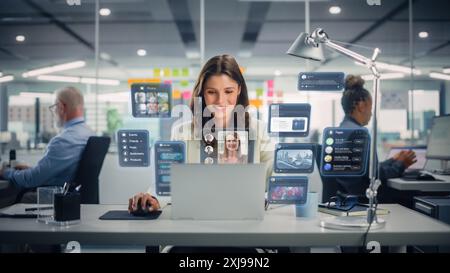 Young Businesswoman Using Laptop Computer in Office with Colleagues. Stylish Social Media Manager Smiling, Working Online Marketing Projects. VFX Hologram Edit Visualizing Social Network With Friends. Stock Photo