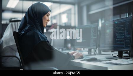 Portrait of a Thoughtful Middle Eastern Female Working on Computer in a Technological Corporate Office. Young Woman Writing Software Code for an Innovative Internet and Software as a Service Project Stock Photo