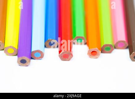 A row of colored pencils with the middle one being red. The pencils are lined up in a row and are of different colors Stock Photo