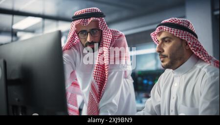 Team of Two Multiethnic Gulf Software Developers Talk, Discuss and Collaborate on an AI Project. Empowered Young Middle Eastern Specialists Work on Digital E-Commerce Startup Business Stock Photo