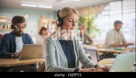 Adult Education Center: Diverse Mature Students Taking Language Exams in Classroom, Using Headphones to Listen to Tasks. Group of People Taking Audio Workshop on Improving Professional Work Skills Stock Photo