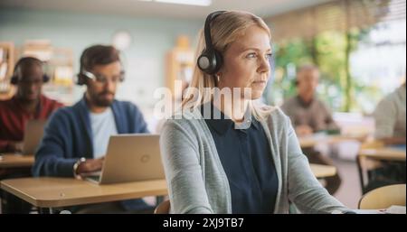 Adult Education Center: Diverse Mature Students Taking Language Exams in Classroom, Using Headphones to Listen to Tasks. Group of People Taking an Audio Workshop on Improving Professional Work Skills Stock Photo