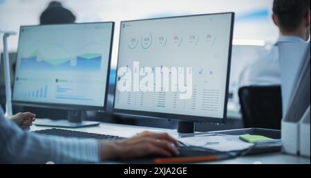 Close Up on Computer Monitors of Male Financial Data Analyst Using Laptop And Studying Information And Graphs On Big Digital Screen In Monitoring Office. Man Working For Big Consulting Firm Stock Photo
