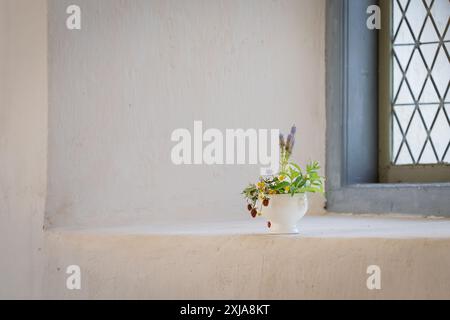 Floral arrangement on a church window sill. Floral arrangement with strawberries and summer flowers. Interior. Stock Photo
