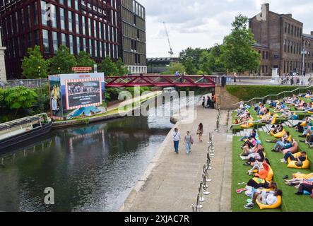 London, England, UK. 17th July, 2024. People watch a screening at the outdoor Everyman cinema on the artificial grass on the steps in Granary Square next to Regent's Canal in King's Cross on a hot day. A health alert has been issued in England as temperatures are predicted to reach 30C on Friday. (Credit Image: © Vuk Valcic/ZUMA Press Wire) EDITORIAL USAGE ONLY! Not for Commercial USAGE! Stock Photo