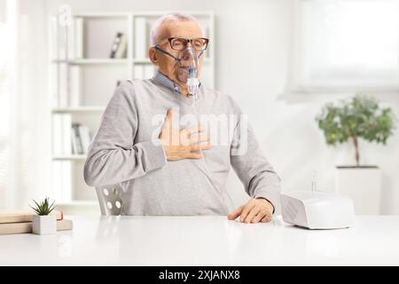 Elderly man with breathing problem using a nebulizer at home Stock Photo