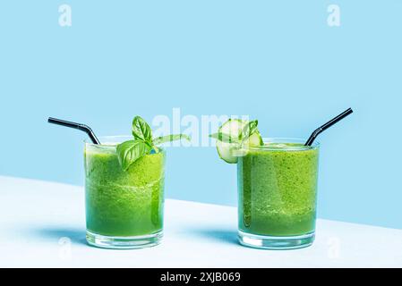 Detox green vegetable smoothie in glasses on light blue background, sunlight, copy space. Healthy clean eating, vegan lifestyle concept. Stock Photo