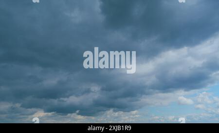 Time lapse. Blue summer sky with thick thunderstorm clouds moving across. Dark grey storm clouds. Stock Photo