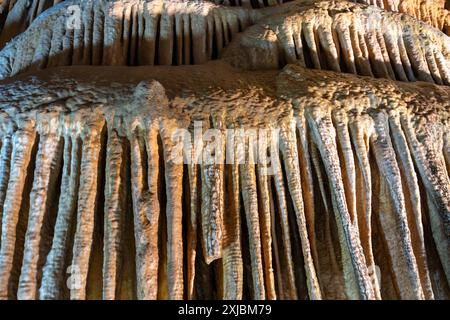 A detailed view of stalactites in a cave, characterized by elongated, drippy formations of limestone and mineral deposits hanging from the cave ceilin Stock Photo