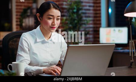 Cheerful businesswoman greeting colleagues during business meeting on videocall in office. Employee speaking in remote videoconference telework call to discuss company matters Stock Photo