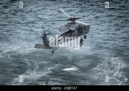 An explosive ordnance disposal technician descends a helicopter during training with the U.S. Navy, Republic of Korea, Germany, Peru, and Japan as part of Exercise Rim of the Pacific (RIMPAC) in Kaneohe Bay, Hawaii, July 16. Twenty-nine nations, 40 surface ships, three submarines, 14 national land forces, more than 150 aircraft and 25,000 personnel are participating in RIMPAC in and around the Hawaiian Islands, June 27 to Aug. 1, 2024. The world’s largest international maritime exercise, RIMPAC, provides a unique training opportunity while fostering and sustaining cooperative relationships amo Stock Photo