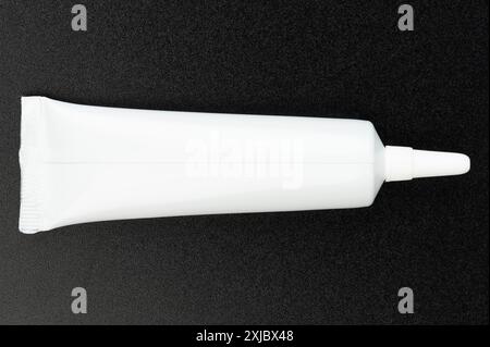 White plastic cream tube isolated on black studio background Stock Photo