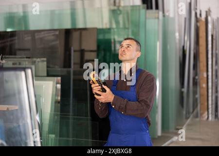 Worker using remote control to operate machinery in glass workshop Stock Photo